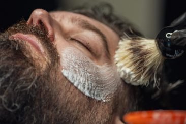 Barbero repasando barba de cliente